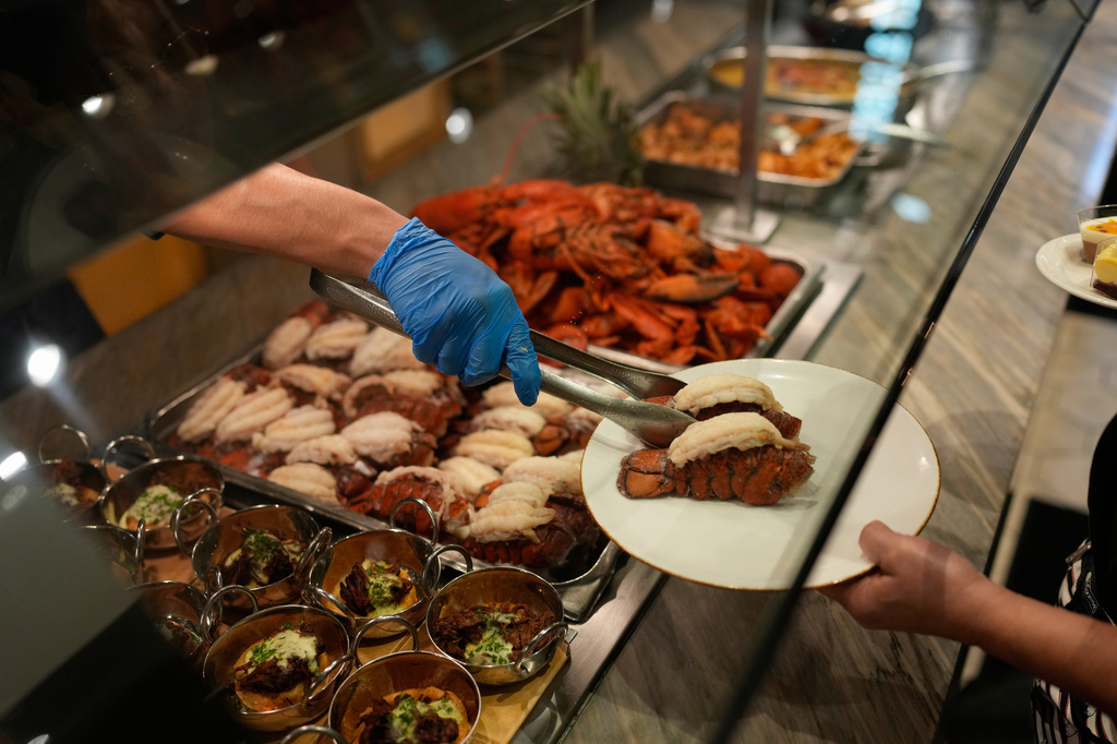 FILE - A person serves lobster tails at the A.Y.C.E Buffet in the Palms resort-casino Wednesday, Jan. 28, 2026, in Las Vegas. (AP Photo/John Locher, File)