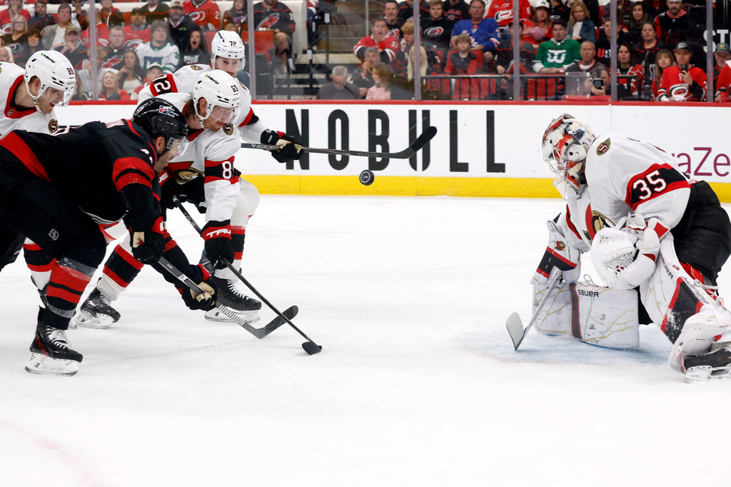 Ottawa Senators goaltender Linus Ullmark (35) watches the puck as Carolina Hurricanes' Jordan Martinook, front left, and Senators' Jake Sanderson (85) clash during the second period of Game 2 of an NHL hockey Stanley Cup first-round playoff series in Raleigh, N.C., Monday, April 20, 2026. (AP Photo/Karl DeBlaker)