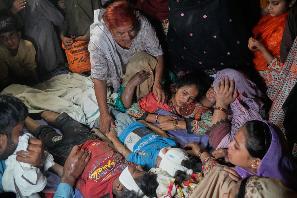 Women mourn next to the bodies of their children killed after the roof of a tutoring center under-construction collapsed, on the outskirts of Lahore, Pakistan, Tuesday, June 30, 2026. (AP Photo/K.M Chaudary)