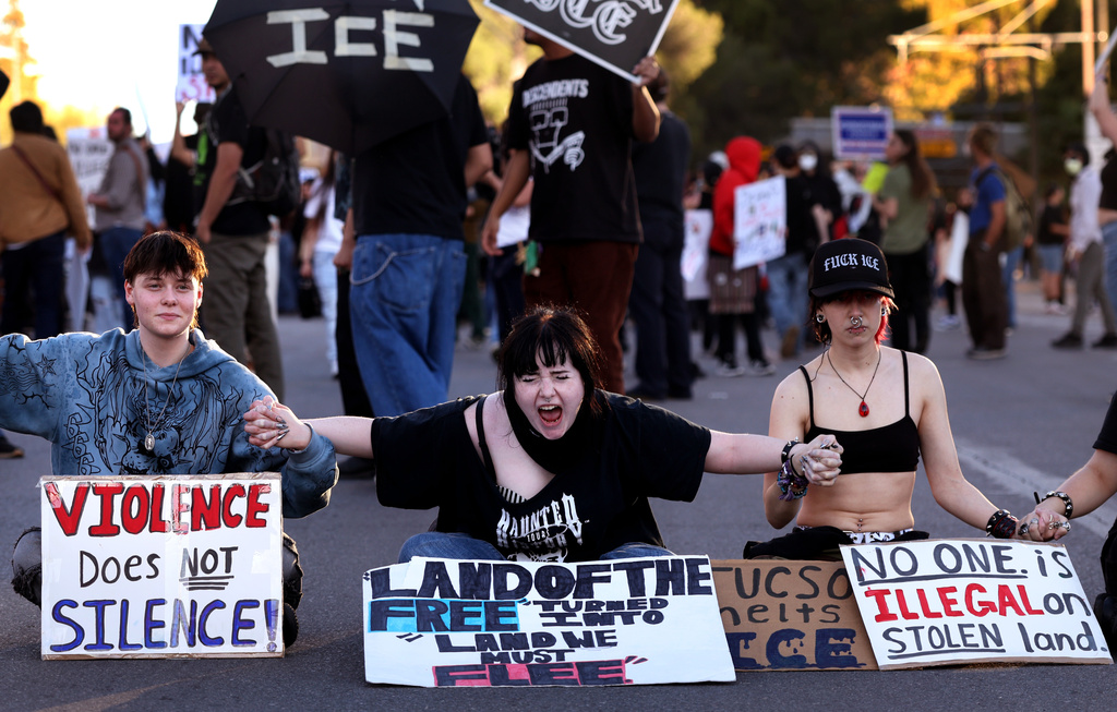 EDS NOTE: OBSCENITY - Demonstrators join hands to block off Congress Street near Granada as the speeches continue through to sunset for the ICE OUT demonstration, Jan. 30, 2026, Tucson, Ariz. (Kelly Presnell/Arizona Daily Star via AP)