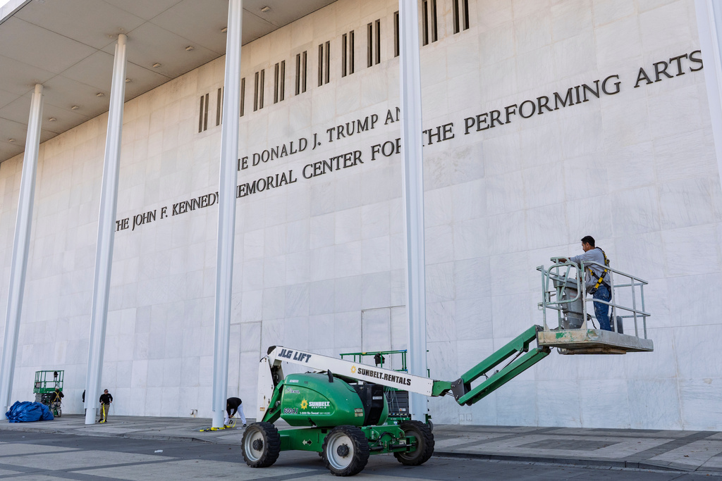 Workers add President Donald Trump's name to the John F. Kennedy Memorial Center for the Performing Arts, after a Trump-appointed board voted to rename the institution, in Washington, Friday, Dec. 19, 2025. (AP Photo/J. Scott Applewhite)