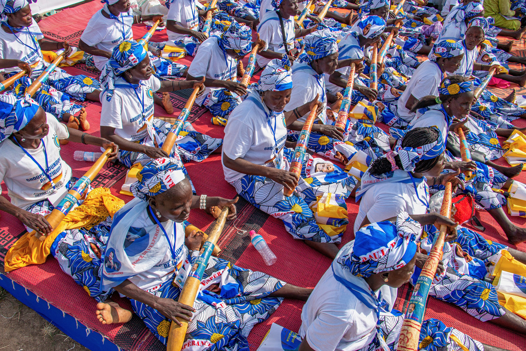 Women dressed in matching patterned outfits hold vuvuzelas printed with the image of President Paul Biya during a political rally at Lamido Yaya Dairou Stadium in Maroua, Cameroon, Tuesday, Oct. 7, 2025. (AP Photo/Welba Yamo Pascal)