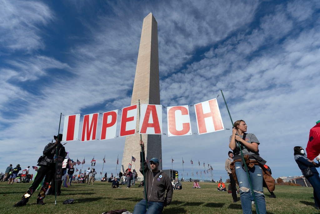Demonstrators holding a sign protest at the Washington Monument during Trump Must Go Now rally at the National Mall in Washington, Wednesday, Nov. 5, 2025. (AP Photo/Jose Luis Magana)