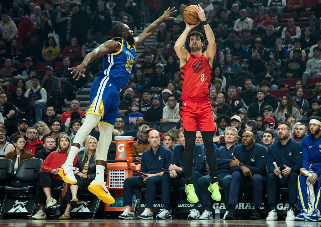 Portland Trail Blazers forward Deni Avdija, right, goes up to shoot over Golden State Warriors forward Draymond Green, left, during the first half of an NBA basketball game in Portland, Ore., Sunday, Dec. 14, 2025. (AP Photo/Craig Mitchelldyer)