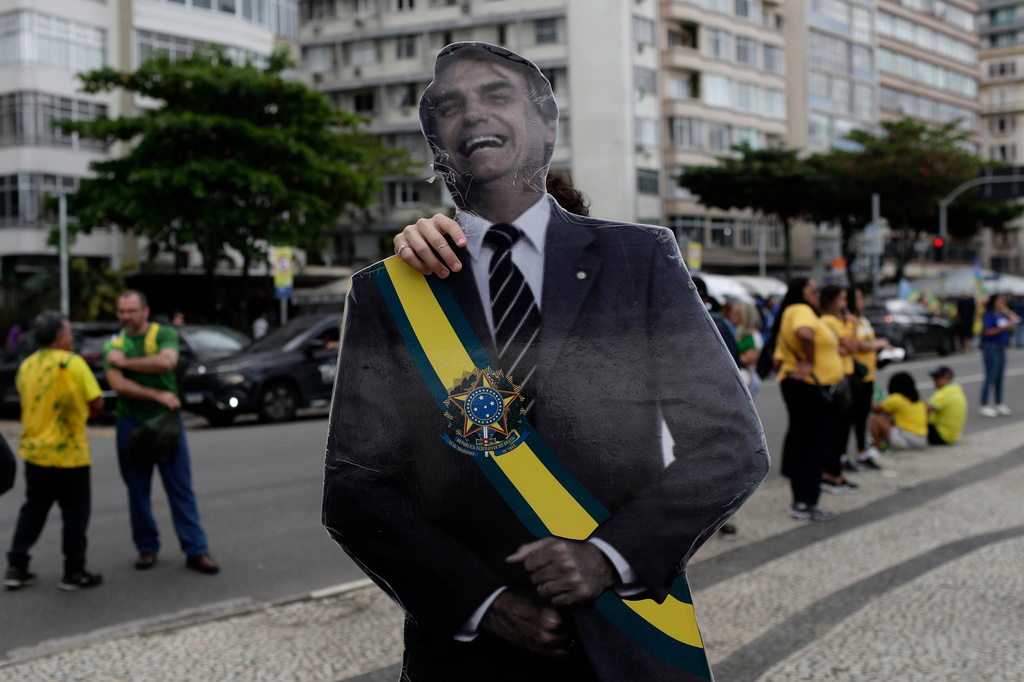 A supporter of opposition presidential candidate Flavio Bolsonaro carries an image of Flavio Bolsonaro's father, former President Jair Bolsonaro, as he arrives for a campaign rally in Rio de Janeiro, Brazil, Sunday, Aug. 16, 2026. (AP Photo/Bruna Prado)