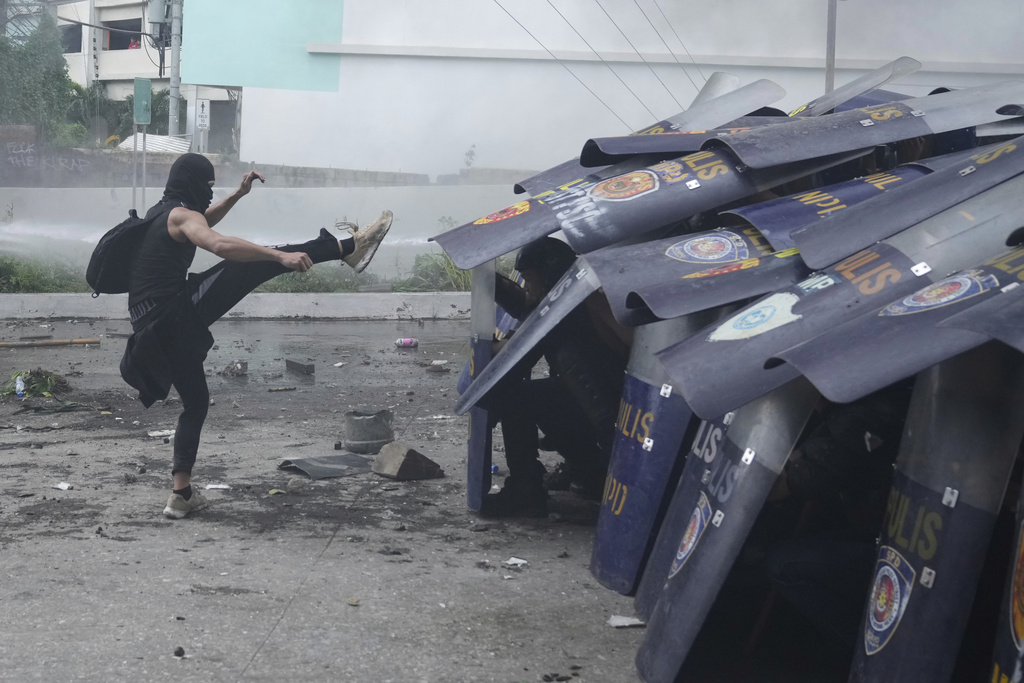 An anti-corruption protester kicks the shield of a policeman during clashes in Manila, Philippines on Sunday, Sept. 21, 2025. (AP Photo/Aaron Favila)