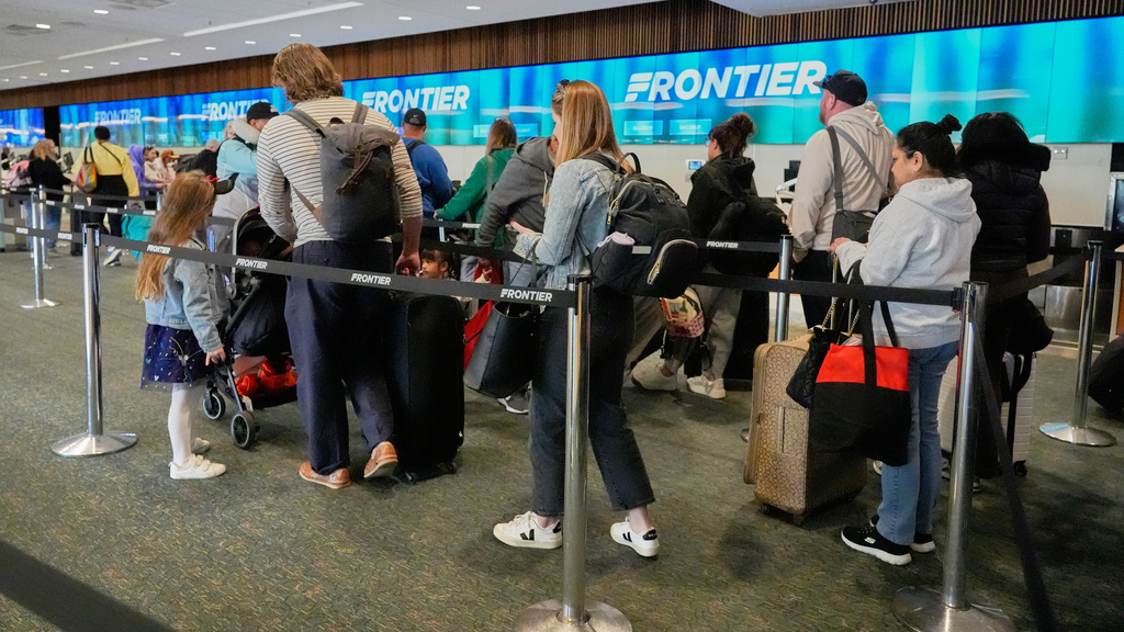 Passengers check in at the Frontier airlines counter at Orlando International Airport Tuesday, Nov. 11, 2025, in Orlando, Fla. (AP Photo/John Raoux)