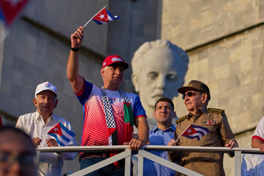 FILE - Cuba's President Miguel Diaz-Canel holds up a Cuban flag as he watches the May Day parade next to Raul Castro, second from right, and Raul Castro's grandson, Raul Guillermo Rodriguez Castro, at Revolution Square in Havana, May 1, 2025. (AP Photo/Ramon Espinosa, File)
