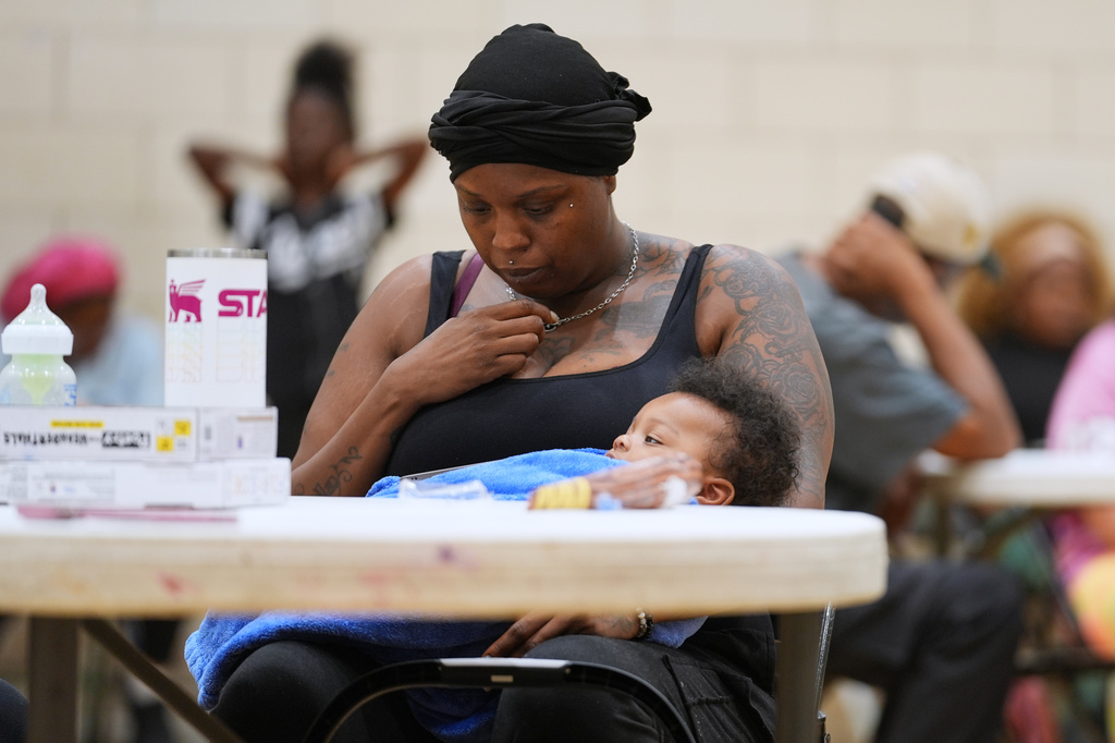 A woman sits inside the City Life Center as she waits for food in Gary, Ind., Thursday, Aug. 20, 2026, more than a week after a deadly storm passed through the area. (AP Photo/Nam Y. Huh)