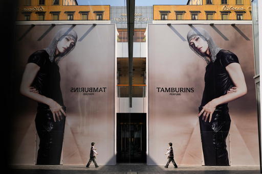A shopper, right, walking under giant advertisements is reflected off the glass wall of a shop at a trendy shopping district during the National Day holidays in Beijing, China, Thursday, Oct. 2, 2025. (AP Photo/Ng Han Guan) A shopper, right, walking under giant advertisements is reflected off the glass wall of a shop at a trendy shopping district during the National Day holidays in Beijing, China, Thursday, Oct. 2, 2025. (AP Photo/Ng Han Guan)