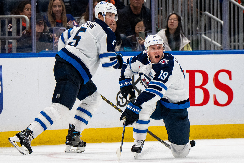 Winnipeg Jets center Jonathan Toews (19) passes the puck during the third period of an NHL hockey game against the New York Islanders, Monday, Oct. 13, 2025, in Elmont, N.Y. (AP Photo/Angelina Katsanis)