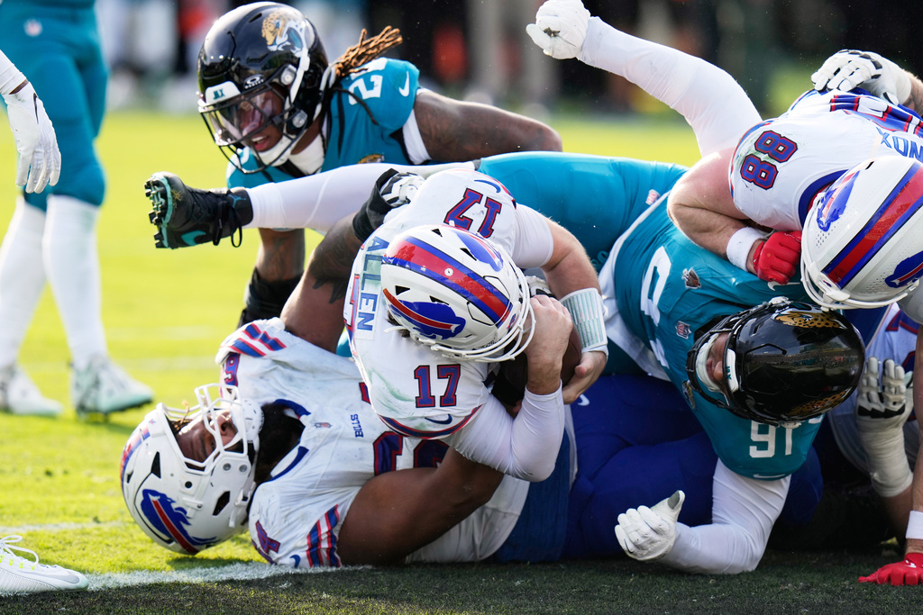 Buffalo Bills quarterback Josh Allen (17) pushes in for a first down as Jacksonville Jaguars defensive tackle Arik Armstead (91) tries to stop him during the second half of an NFL wild-card playoff football game Sunday, Jan. 11, 2026, in Jacksonville, Fla. (AP Photo/Chris O'Meara)