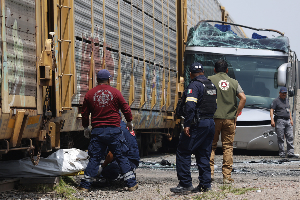 Rescue workers remove a body at the scene of a deadly accident where a freight train slammed into a double-deck bus in Atlacomulco, Mexico, Monday, Sept. 8, 2025. (AP Photo/Ramses Mercado Valdes)