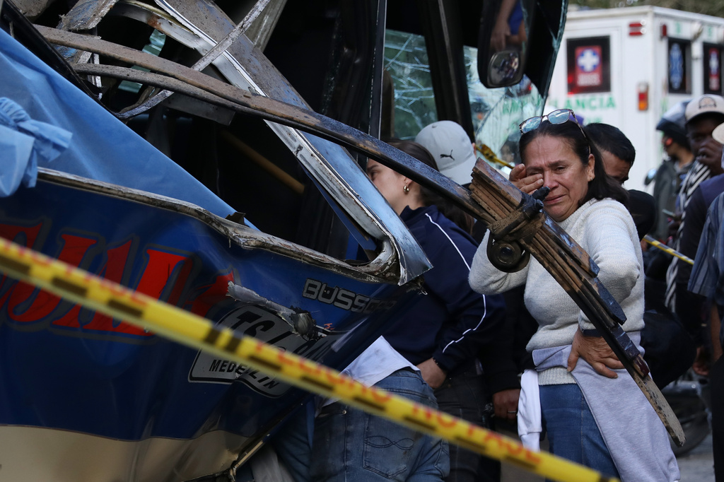 People gather around a bus hit by an explosive device on the Pan-American Highway in Cajibio, Colombia, Saturday, April 25, 2026, after an attack blamed by authorities on dissident groups of the former FARC rebels killed at least a dozen people. (AP Photo/Santiago Saldarriaga)