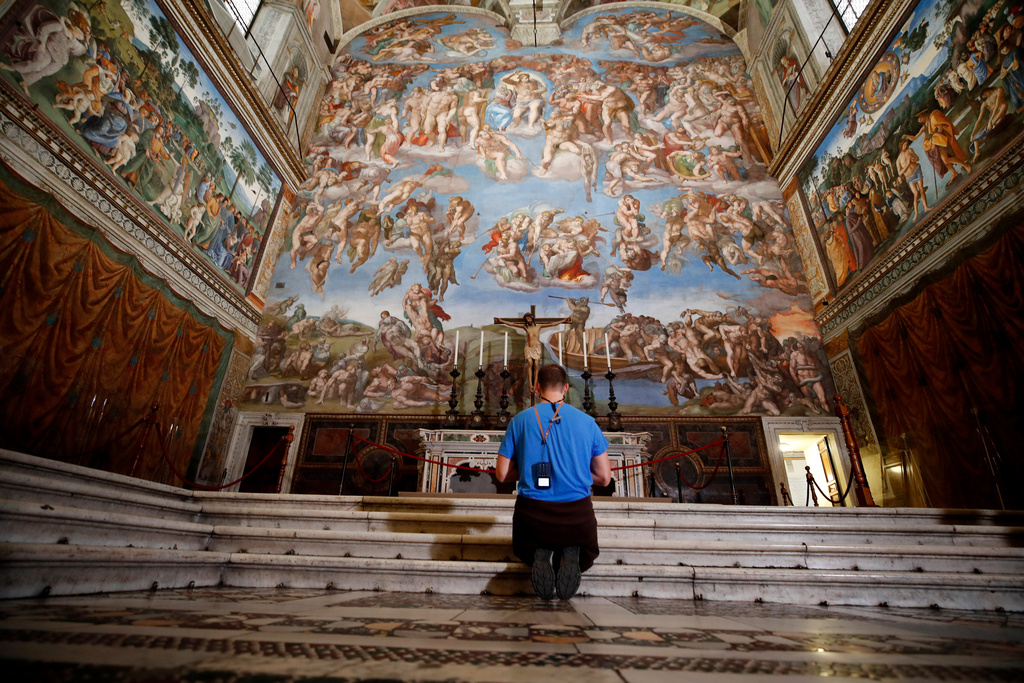 FILE - A visitor kneels in front of the Last Judgement fresco by the Italian Renaissance painter Michelangelo inside the Sistine Chapel in Rome, May 3, 2021. (AP Photo/Alessandra Tarantino, File)