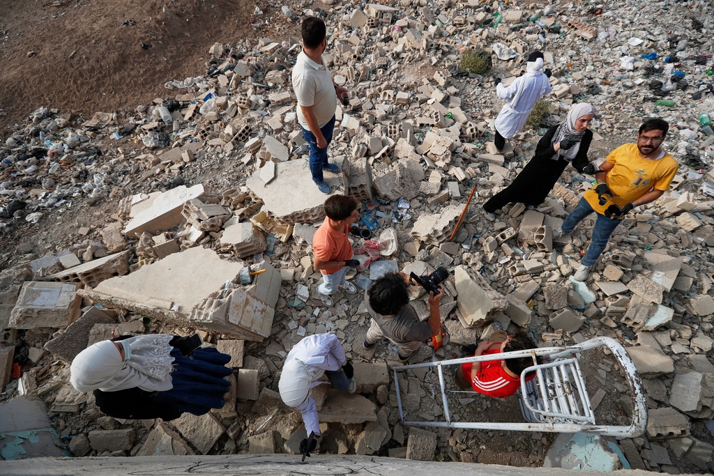A group of Syrian graffiti artists look at a mural they painted on the collapsed ceiling of a war-damaged house in Daraya, on the outskirts of Damascus, Syria, Monday, Nov. 3, 2025. (AP Photo/Omar Sanadiki)