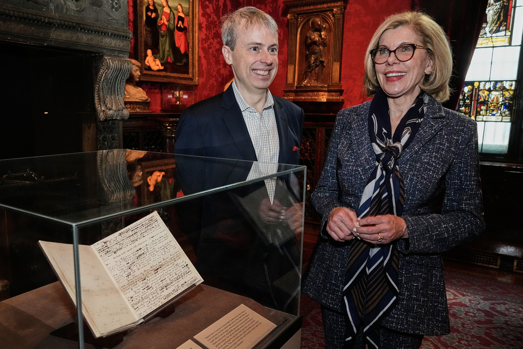 Skylark Artistic Director Matthew Guard and Christine Baranski are interviewed beside "A Christmas Carol In Prose; Being a Ghost Story of Christmas" by Charles Dickens, Dec. 1843," at The Morgan Library & Museum, in New York, Monday, Dec. 1, 2025. (AP Photo/Richard Drew)