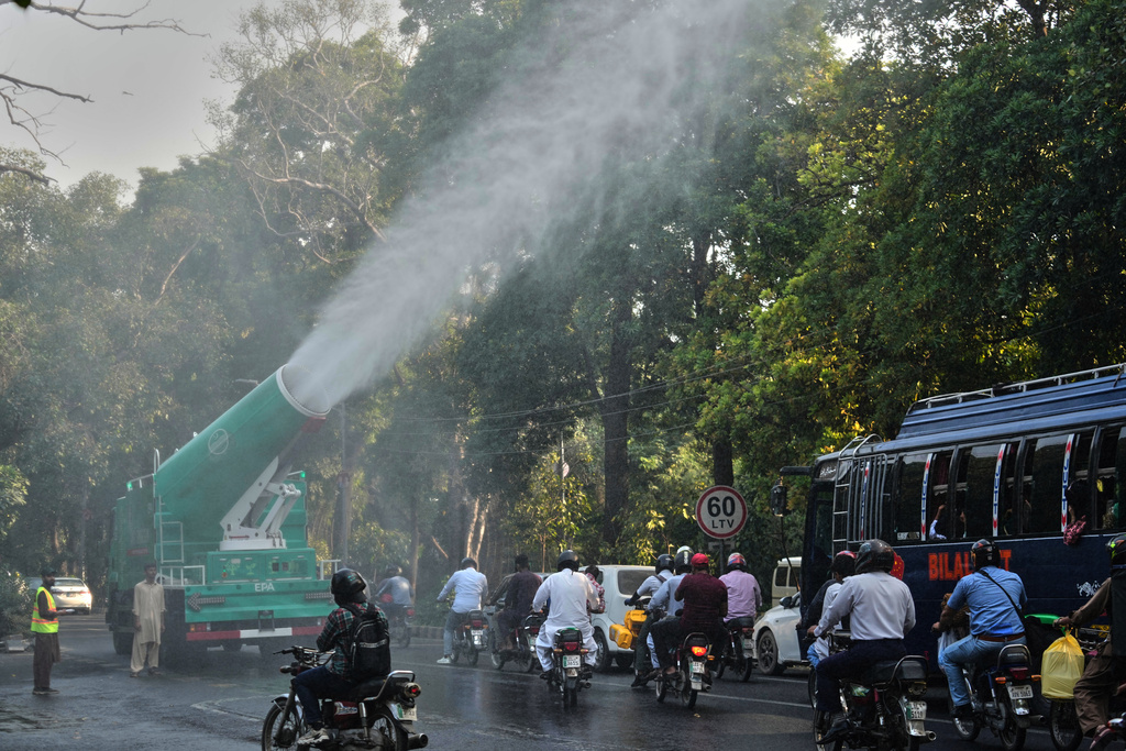 Workers of Environment Protection Agency spray water with anti-smog guns at a road in Lahore, Pakistan, Thursday, Oct. 23, 2025. (AP Photo/K.M. Chaudary)