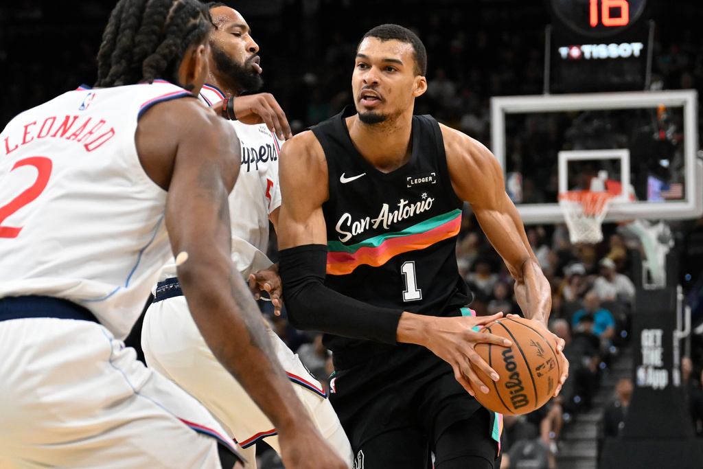 San Antonio Spurs center Victor Wembanyama (1) drives against Los Angeles Clippers' Derrick Jones Jr., second from right, and Kawhi Leonard (2) during the first half of an NBA basketball game, Friday, March 6, 2026, in San Antonio. (AP Photo/Darren Abate)