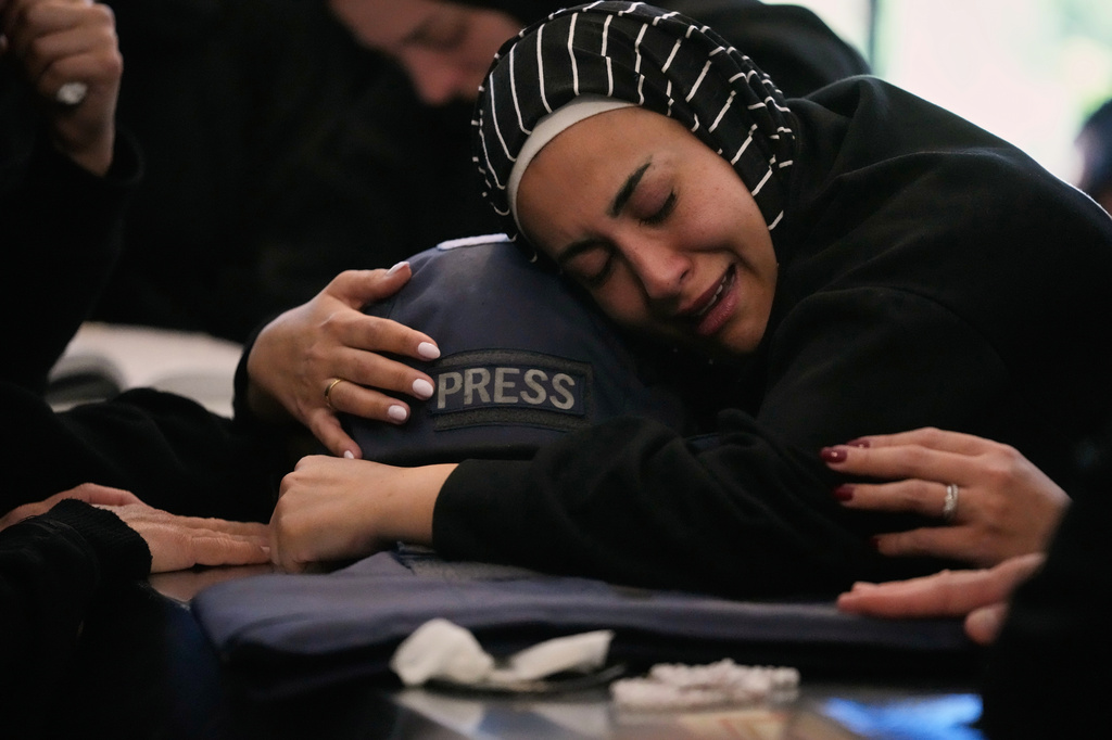 Zainab, the sister of Lebanese journalist Amal Khalil, who was killed on Wednesday in an Israeli airstrike, hugs her helmet as she mourns over her coffin in the village of Baysariyeh, southern Lebanon, Thursday, April 23, 2026. (AP Photo/Mohammed Zaatari)