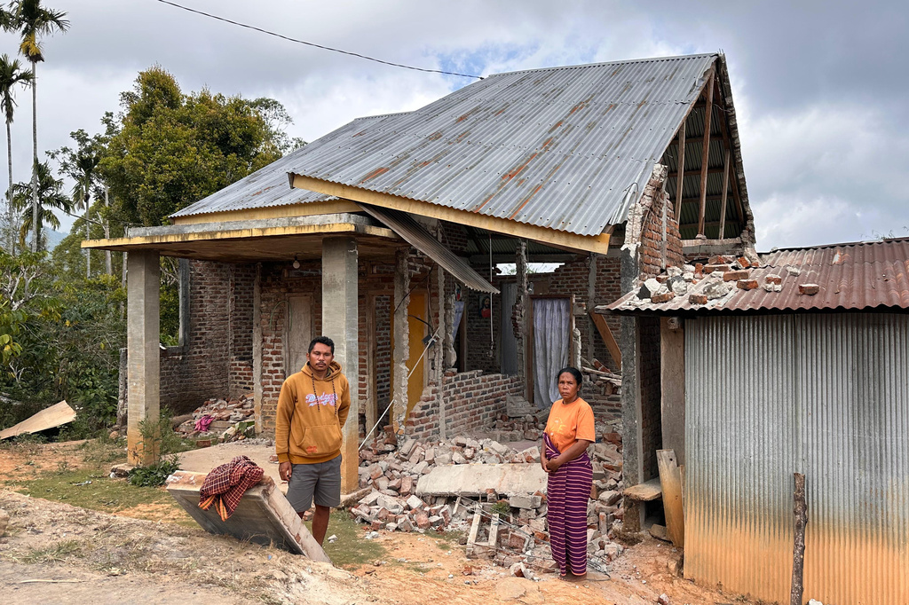 Maria Imakulata Ndue, right, and her son Yohanes Defrianus Ratu stand outside their earthquake-damaged house in Lembor, East Nusa Tenggara province, Indonesia, Sunday, Aug. 16, 2026. (AP Photo/Firdia Lisnawati)