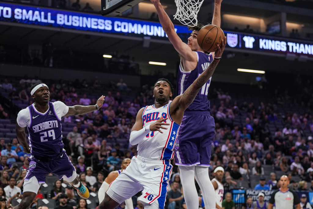 Philadelphia 76ers forward Justin Edwards, front, goes for a layup against Sacramento Kings center Maxime Raynaud, rear right, during the first half of an NBA basketball game, Thursday, March 19, 2026, in Sacramento, Calif. (AP Photo/Justine Willard)