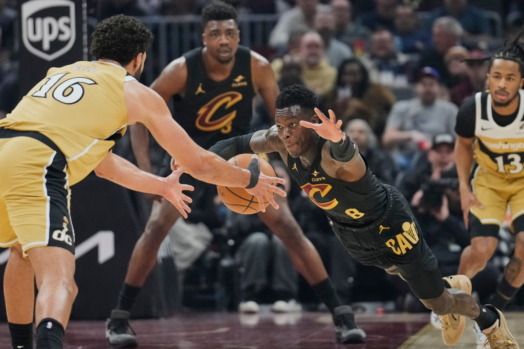 Washington Wizards forward Anthony Gill (16) and Cleveland Cavaliers' Dennis Schroder (8) reach for the ball in the first half of an NBA basketball game in Cleveland, Wednesday, Feb. 11, 2026. (AP Photo/Sue Ogrocki)