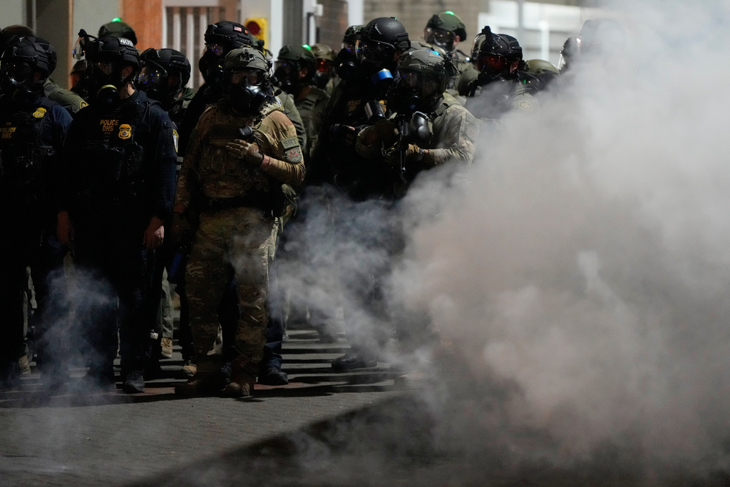 Law enforcement officers stand in tear gas outside a U.S. Immigration and Customs Enforcement facility during a protest on Saturday, Oct. 4, 2025, in Portland, Ore. (AP Photo/Jenny Kane)