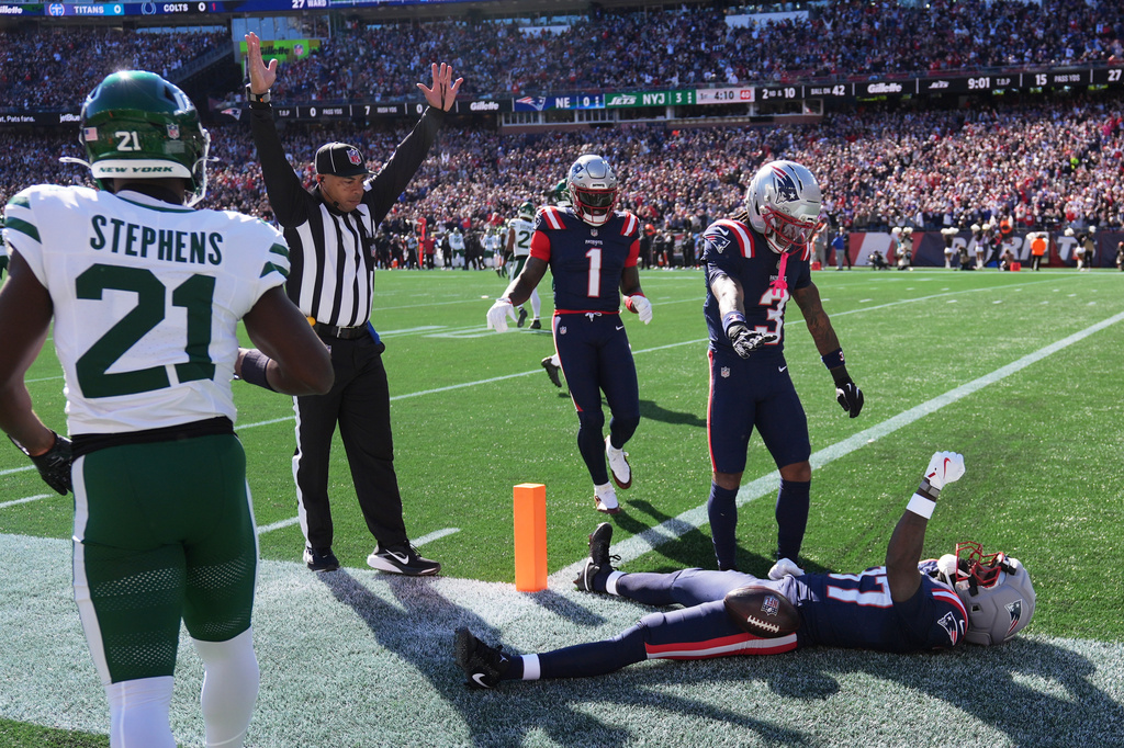 New England Patriots wide receiver Romeo Doubs, on ground, celebrates after scoring a touchdown during the first half of an NFL football game against the New York Jets in Foxborough, Mass., Sunday, Oct. 18, 2026. (AP Photo/Charles Krupa)