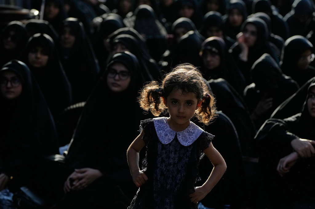 A girl looks on as women sit during a mourning ceremony in Tehran, Iran, Thursday, June 18, 2026, ahead of Ashoura, which honors the 7th-century martyrdom of the Prophet Muhammad's grandson, Hussein, who was killed in a battle in Karbala in present-day Iraq. (AP Photo/Vahid Salemi)