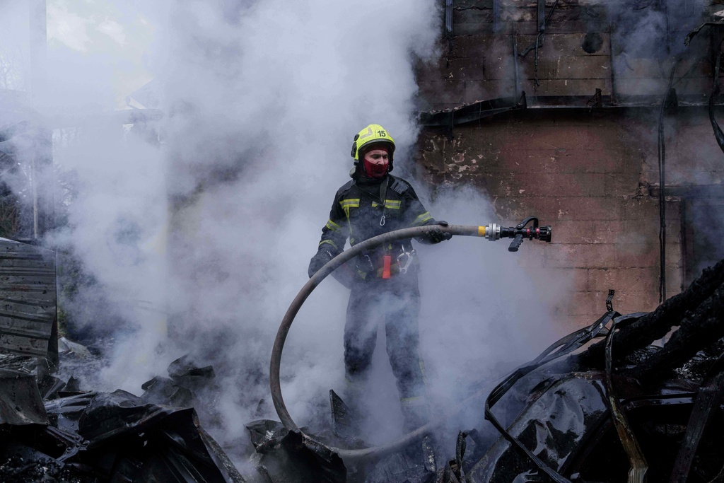 A rescue worker puts out a fire of a house destroyed after a Russian strike on Kyiv, Ukraine, on Saturday, Dec. 27, 2025. (AP Photo/Evgeniy Maloletka)