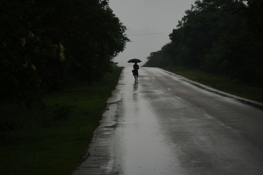 A man walks in the rain before the arrival of Hurricane Melissa in Canizo, a community in Santiago de Cuba, Tuesday, Oct. 28, 2025. (AP Photo/Ramon Espinosa)