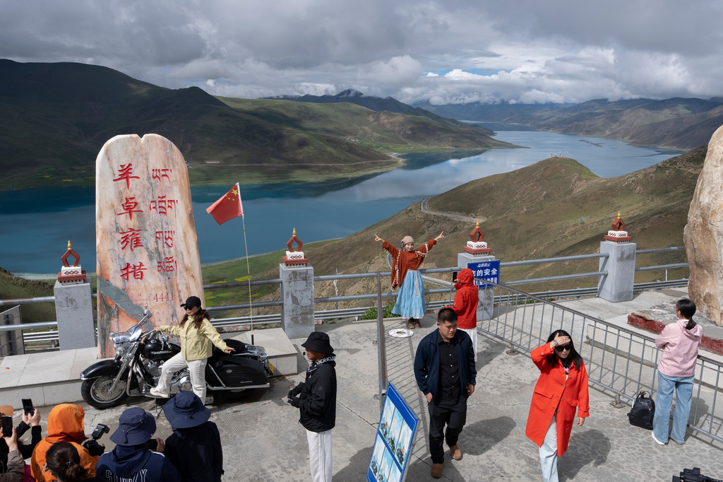 Visitors pose for photos from a viewing platform overlooking Yamdrok Lake in western China's Tibet Autonomous Region on Thursday, July 23, 2026, as seen during a government organized visit for foreign journalists. (AP Photo/Ng Han Guan)
