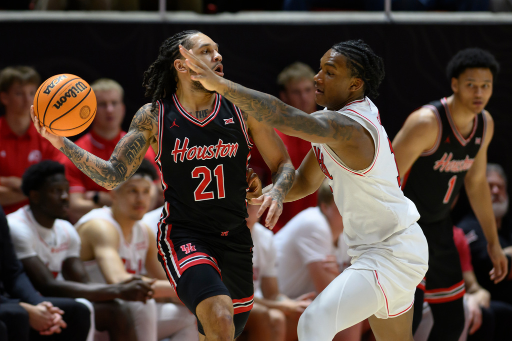 Houston guard Emanuel Sharp, left, looks to pass around the defense of Utah forward Kendyl Sanders, right, during the first half of an NCAA college basketball game, Tuesday, Feb. 10, 2026, in Salt Lake City. (AP Photo/Tyler Tate)
