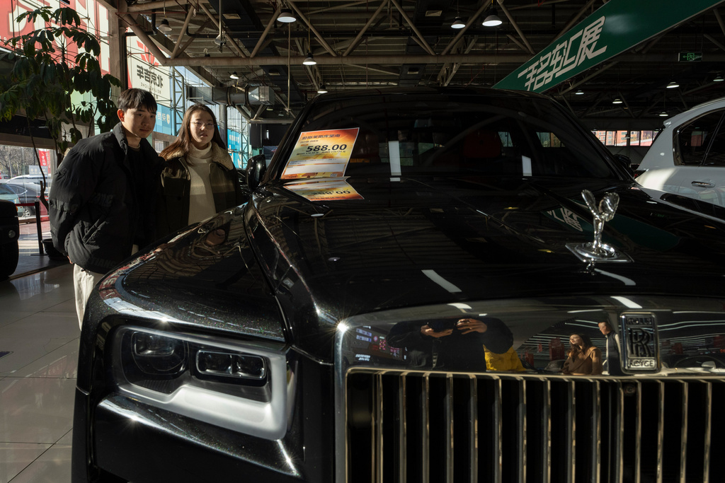 Visitors look at a second hand luxury car for sale in Beijing on Friday, Nov. 21, 2025. (AP Photo/Ng Han Guan)