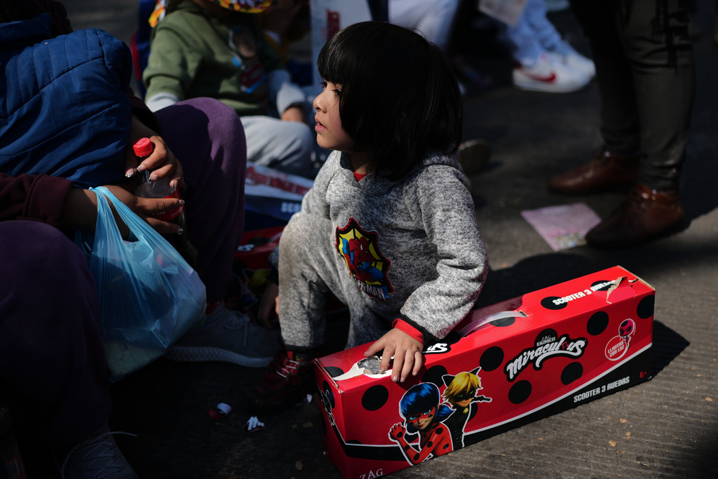 A child sits with their free gift at an event celebrating Three Kings Day, at the Angel of Independence in Mexico City, Monday, Jan. 5, 2026. (AP Photo/Marco Ugarte)