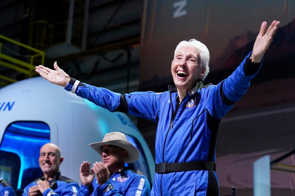 FILE - Wally Funk, right, describes her flight experience as Mark Bezos, left, and Jeff Bezos, left, center, applaud in the spaceport near Van Horn, Texas, July 20, 2021. (AP Photo/Tony Gutierrez, File)