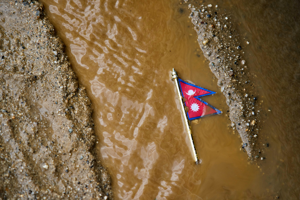 A Nepal flag lies on a muddy track near the banks of the Trishuli river in Dhading District, Nepal, Sunday, Aug. 30, 2026. (AP Photo/Niranjan Shrestha)