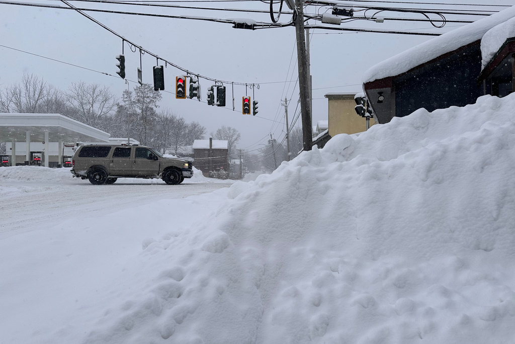 Traffic passes piled-up snow in Lowville, N.Y., Tuesday, Jan. 20, 2026. (AP Photo/Cara Anna)