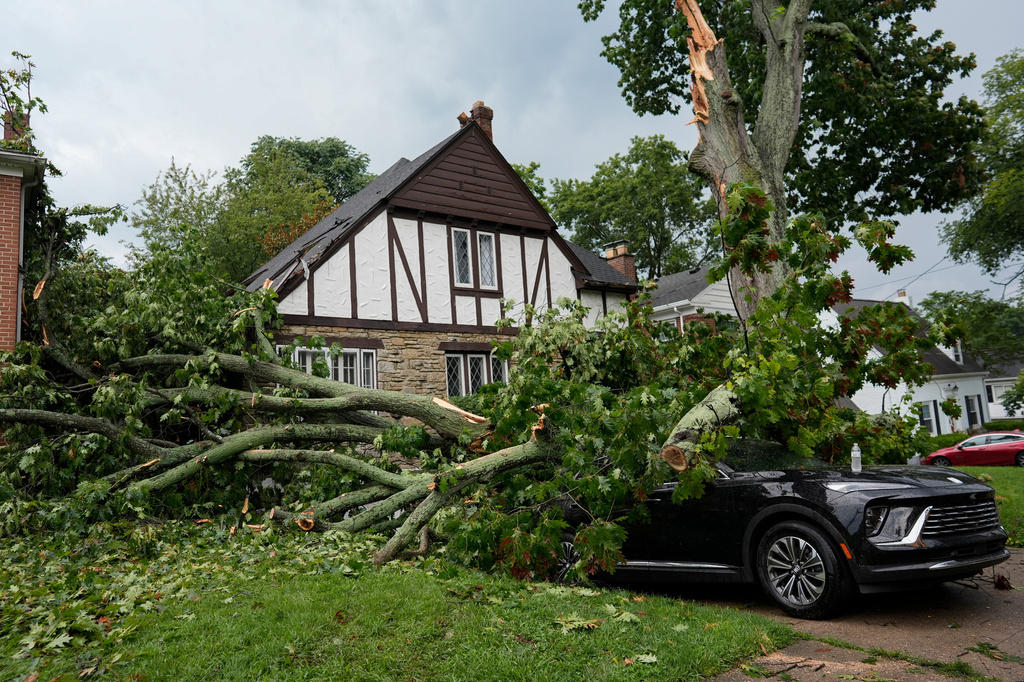 A car is destroyed and homes damaged by part of an oak tree downed by severe storms Tuesday, is seen in Cincinnati on Wednesday, Aug. 12, 2026. (AP Photo/Carolyn Kaster)