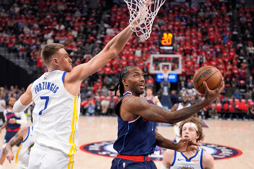 LA Clippers forward Kawhi Leonard, center, shoots as Golden State Warriors center Kristaps Porzingis defends during the first half of an NBA play-in tournament basketball game Wednesday, April 15, 2026, in Inglewood, Calif. (AP Photo/Mark J. Terrill)