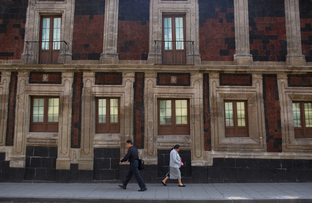 FILE - Pedestrians walk past a slightly tilted historic building in downtown Mexico City, June 15, 2016. The city was built on a drained lake bed and many buildings are noticeably tilted, from sinking unevenly into the soft earth over decades or centuries. (AP Photo/Rebecca Blackwell, File)