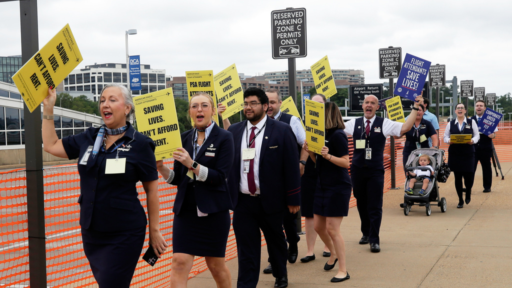 PSA Airlines flight attendants hold placards during a demonstration at Ronald Reagan Washington National Airport, Monday, August 18, 2025, in Washington. (AP Photo/Rahmat Gul)