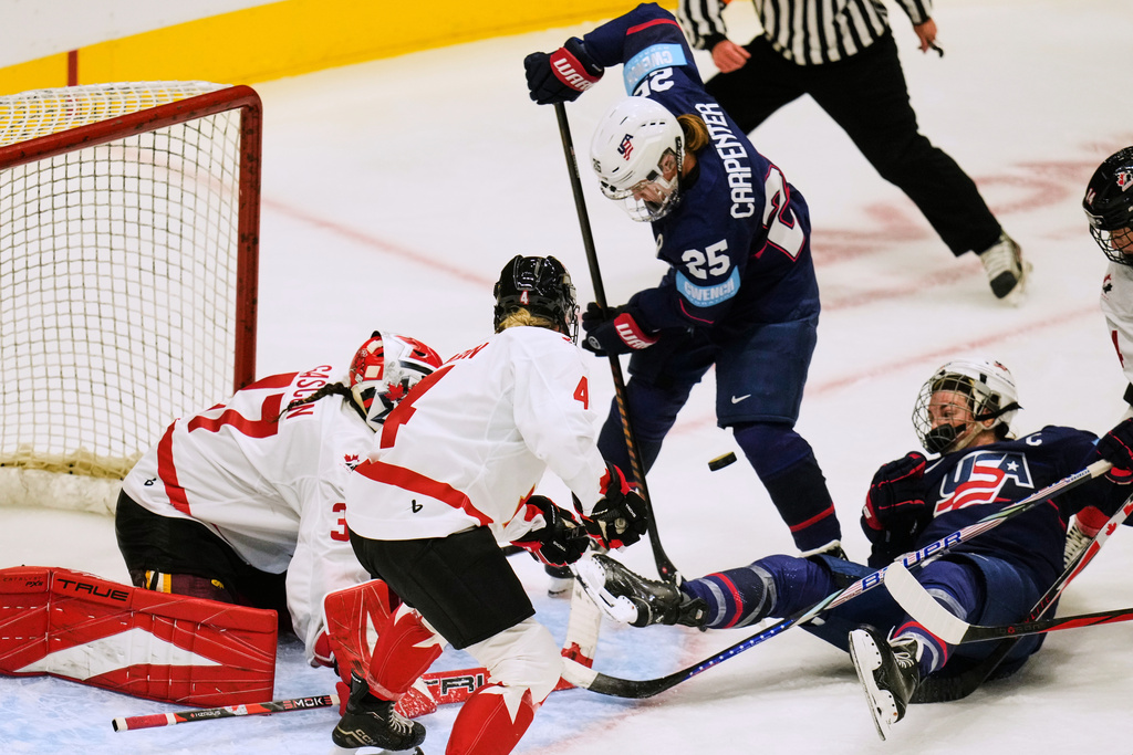 United States forward Hillary Knight, bottom right, watches the puck as Canada goaltender Eve Gascon, left, and Katie Tabin (4) defend againstUnited States' Alex Carpenter (25) in the third period of a Rivalry Series women's hockey game Thursday, Nov. 6, 2025, in Cleveland. (AP Photo/Sue Ogrocki)