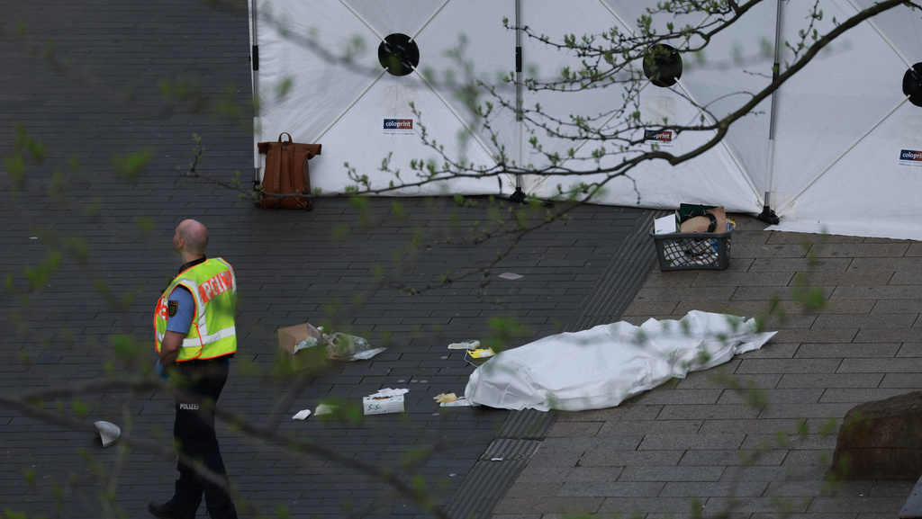 A policeman stands next to a body bag after a car crashed into several people in Leipzig, Germany, Monday, May 4, 2026. (Jan Woitas/dpa via AP)
