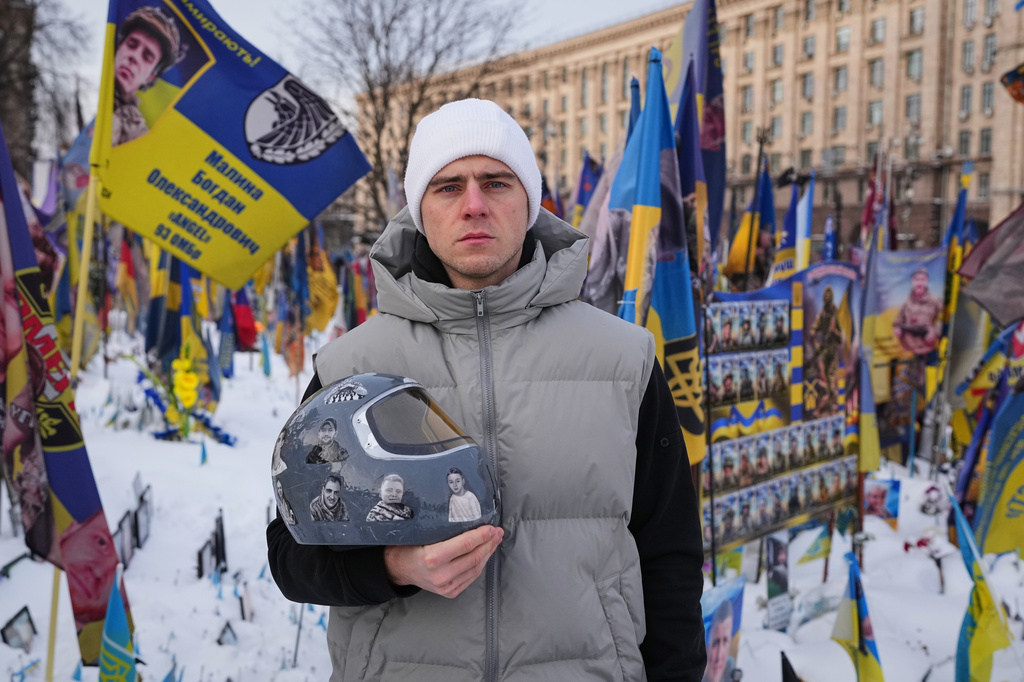 FILE - Ukrainian skeleton athlete Vladyslav Heraskevych holds his crash helmet as he stands outside an improvised memorial to fallen soldiers killed in the war at Independence square in Kyiv, Ukraine, Feb. 18, 2026. (AP Photo/Sergei Grits, File)