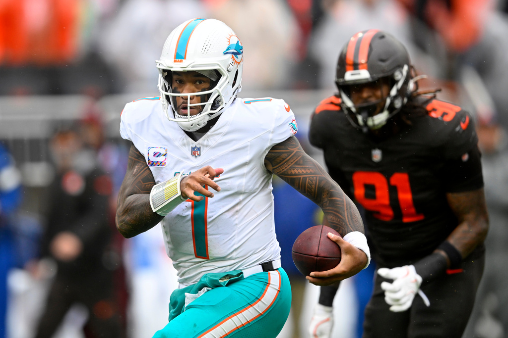 Miami Dolphins quarterback Tua Tagovailoa (1) scrambles from Cleveland Browns defensive end Alex Wright (91) in the first half of an NFL football game in Cleveland, Sunday, Oct. 19, 2025. (AP Photo/David Richard)