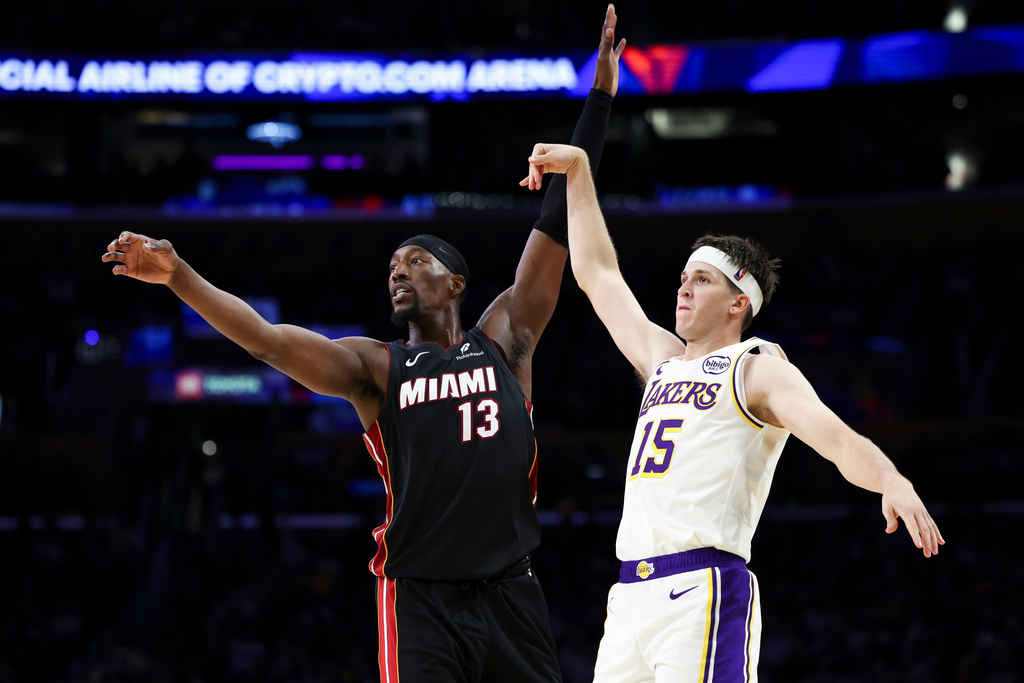 Los Angeles Lakers guard Austin Reaves (15) follows through on a 3-point basket as Miami Heat center Bam Adebayo (13) watches during the first half of an NBA basketball game, Sunday, Nov. 2, 2025, in Los Angeles. (AP Photo/Jessie Alcheh)