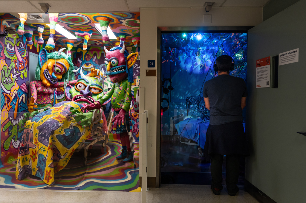 A visitor views an installation by Margüi while standing beside an installation by Guy "Dioz" Bloom during the "Hospital of Emotions" exhibition inside a former hospital building in Los Angeles, Wednesday, July 22, 2026. (AP Photo/Jae C. Hong)