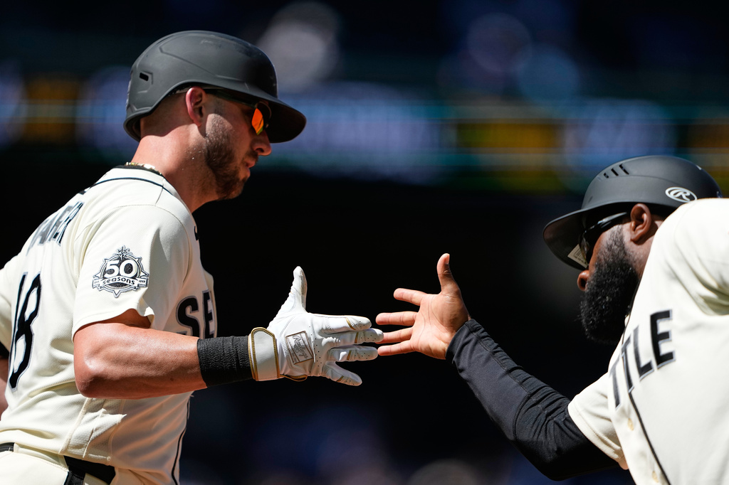 Seattle Mariners' Mitch Garver greets first base coach Eric Young Jr. after hitting a two-run home run against the Toronto Blue Jays during the fourth inning of a baseball game, Sunday, July 5, 2026, in Seattle. (AP Photo/Lindsey Wasson)